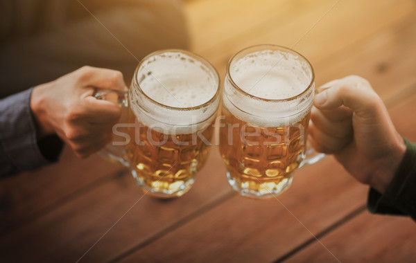 Stock photo: close up of hands with beer mugs at bar or pub