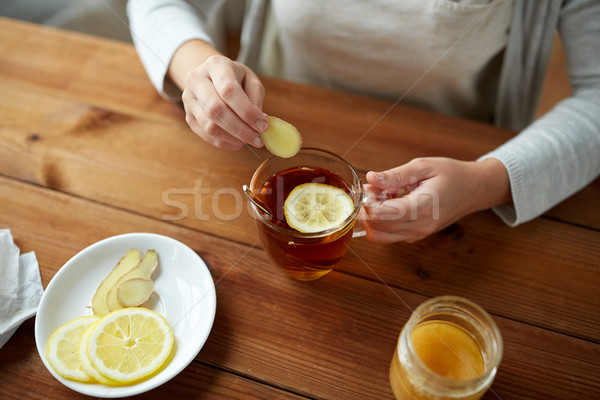 close up of woman adding ginger to tea with lemon Stock photo © dolgachov