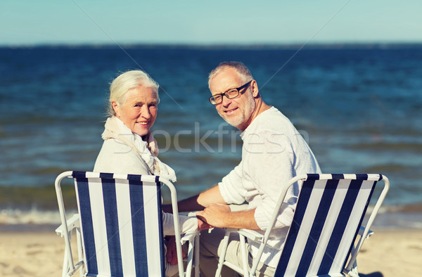 senior couple sitting on chairs at summer beach Stock photo © dolgachov