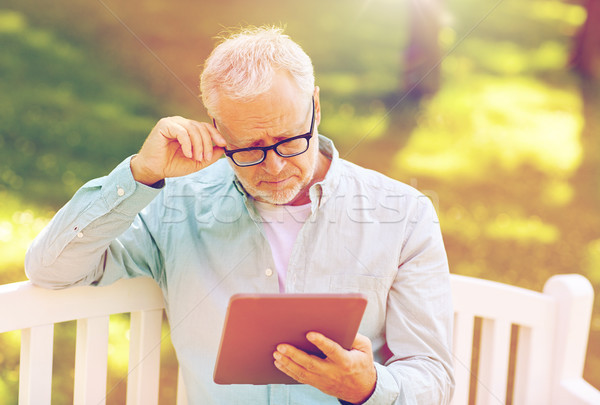 senior man with tablet pc at summer park Stock photo © dolgachov