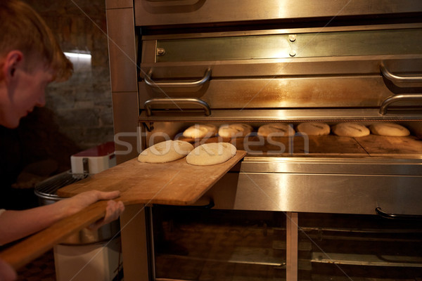 baker putting dough into bread oven at bakery Stock photo © dolgachov