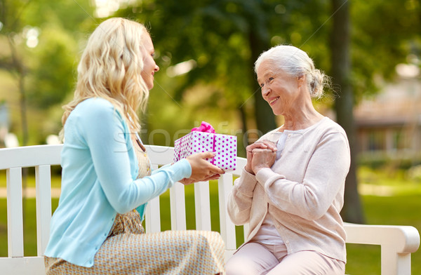 daughter giving present to senior mother at park Stock photo © dolgachov