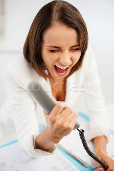 woman shouting into phone in office Stock photo © dolgachov