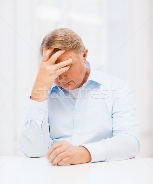 stressed old man holding head at home Stock photo © dolgachov