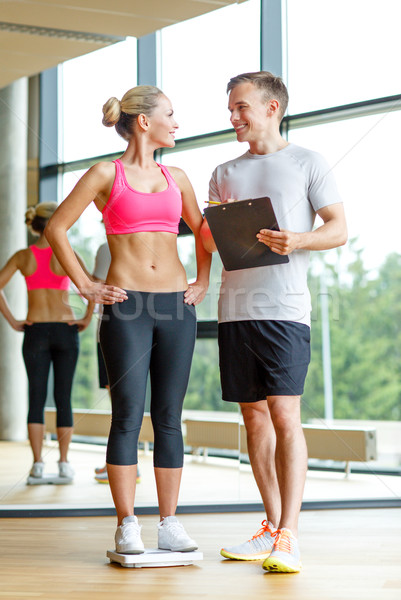 smiling man and woman with scales in gym Stock photo © dolgachov