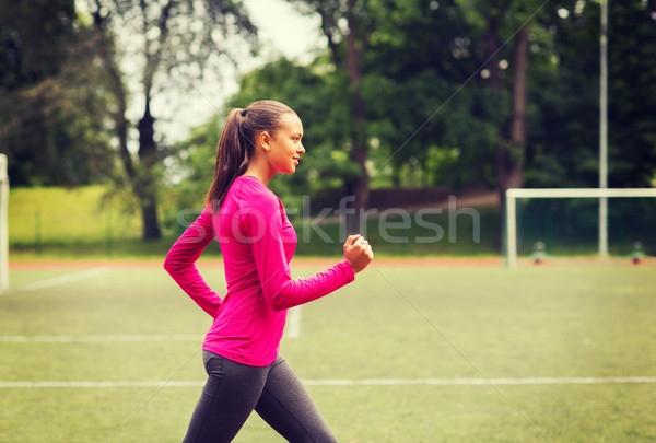 smiling young woman running on track outdoors Stock photo © dolgachov