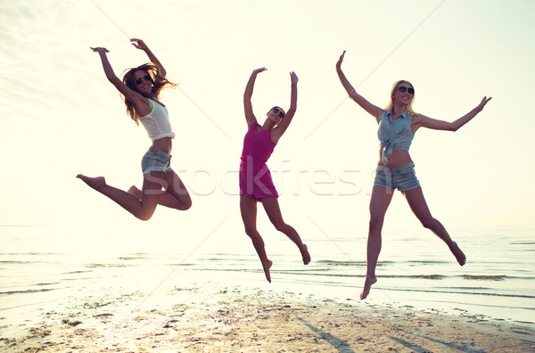 happy female friends dancing and jumping on beach Stock photo © dolgachov