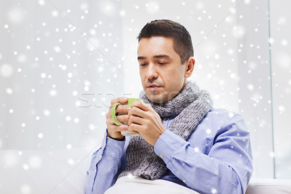 ill man with flu drinking hot tea from cup at home Stock photo © dolgachov