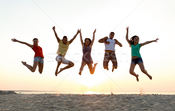 smiling friends dancing and jumping on beach Stock photo © dolgachov