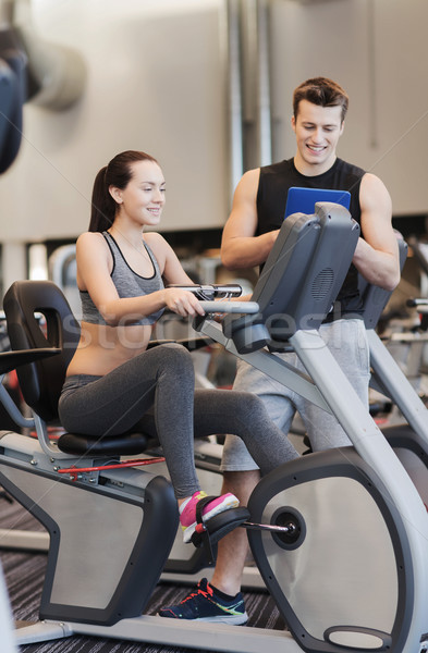 happy woman with trainer on exercise bike in gym Stock photo © dolgachov