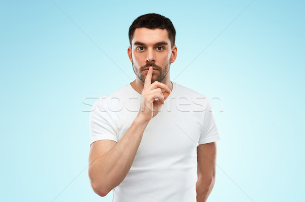 young man making hush sign over blue background Stock photo © dolgachov