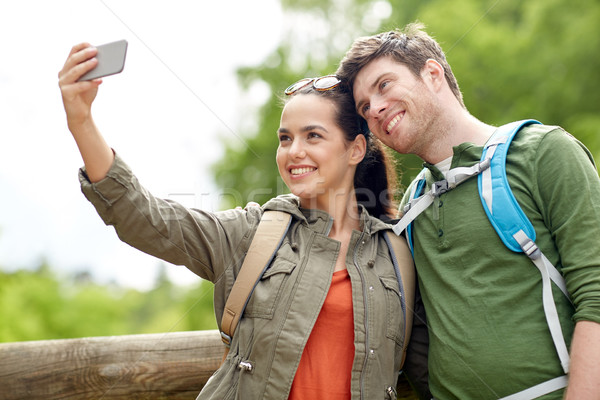 couple with backpacks taking selfie by smartphone Stock photo © dolgachov