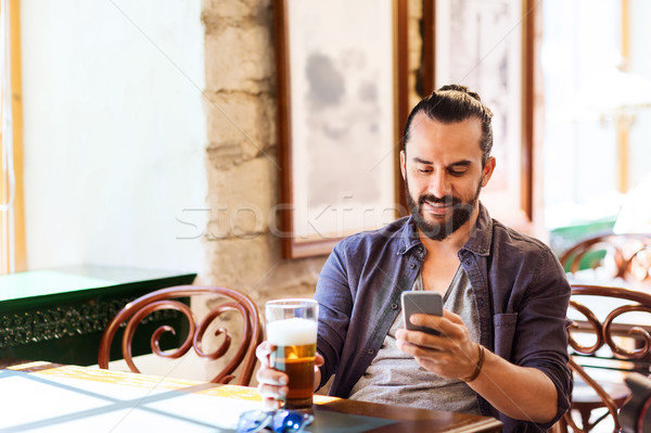 man with smartphone drinking beer at bar or pub Stock photo © dolgachov