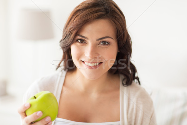 smiling young woman eating green apple at home Stock photo © dolgachov