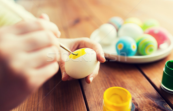 Stock photo: close up of woman hands coloring easter eggs