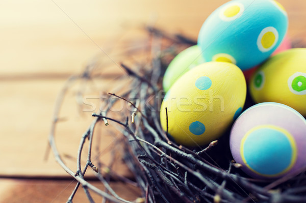 close up of colored easter eggs in nest on wood Stock photo © dolgachov