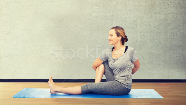 woman making yoga in twist pose on mat Stock photo © dolgachov