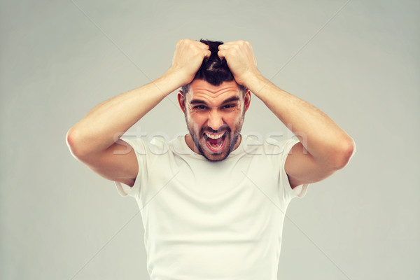 crazy shouting man in t-shirt over gray background Stock photo © dolgachov