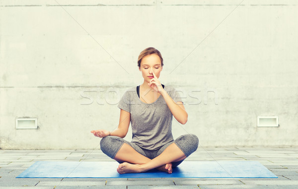 woman making yoga meditation in lotus pose on mat Stock photo © dolgachov