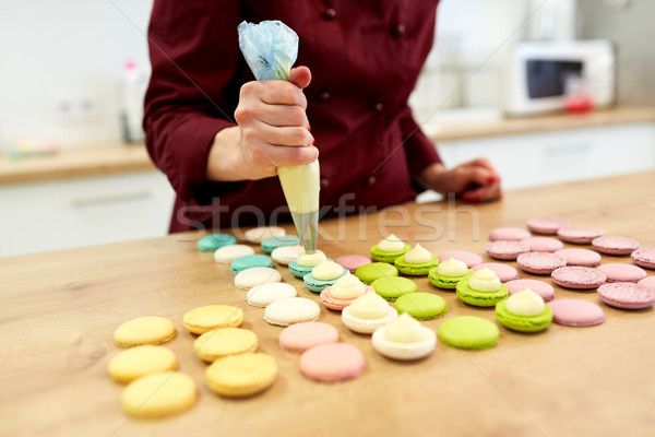 chef with injector squeezing filling to macarons Stock photo © dolgachov