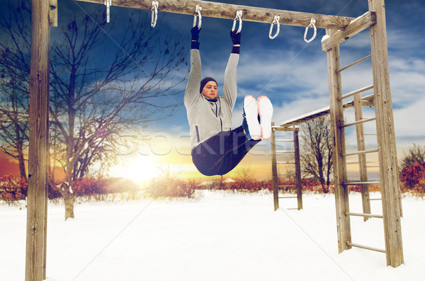 young man exercising on horizontal bar in winter Stock photo © dolgachov