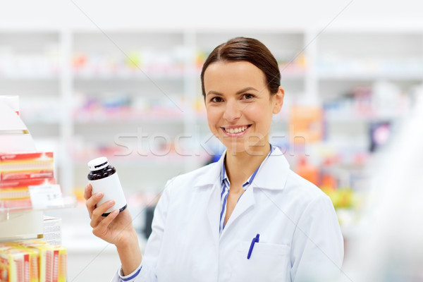happy female apothecary with drug at pharmacy Stock photo © dolgachov