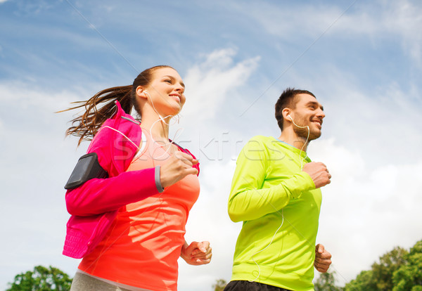 smiling couple with earphones running outdoors Stock photo © dolgachov