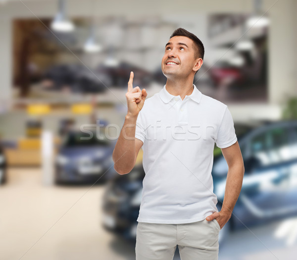 Stock photo: smiling man pointing finger up over auto show