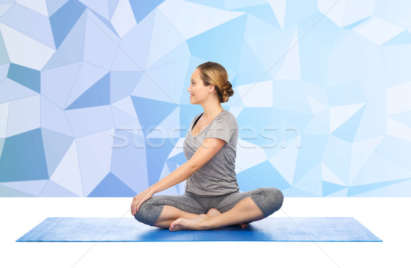 woman making yoga in twist pose on mat Stock photo © dolgachov