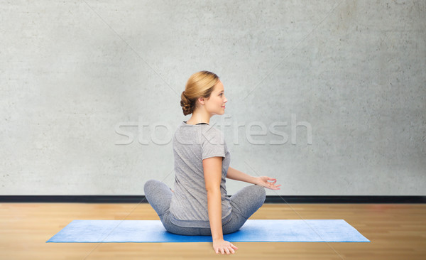 woman making yoga in twist pose on mat Stock photo © dolgachov