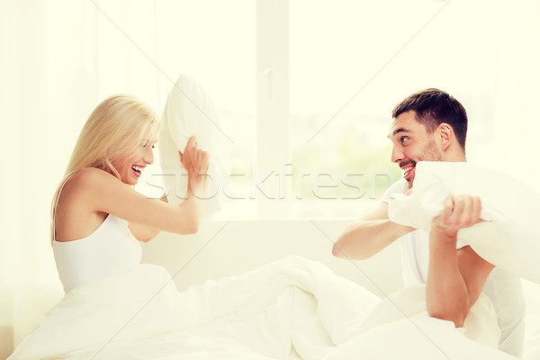 Heureux couple bataille d'oreillers lit maison personnes [[stock_photo]] © dolgachov