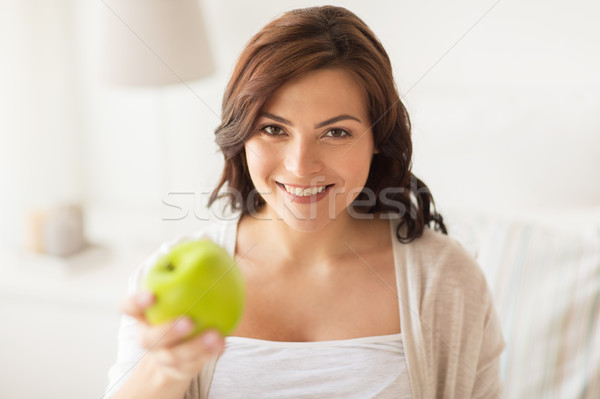 smiling young woman eating green apple at home Stock photo © dolgachov