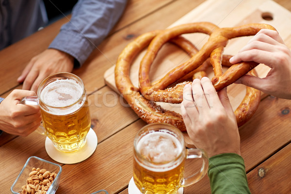 close up of men drinking beer with pretzels at pub Stock photo © dolgachov
