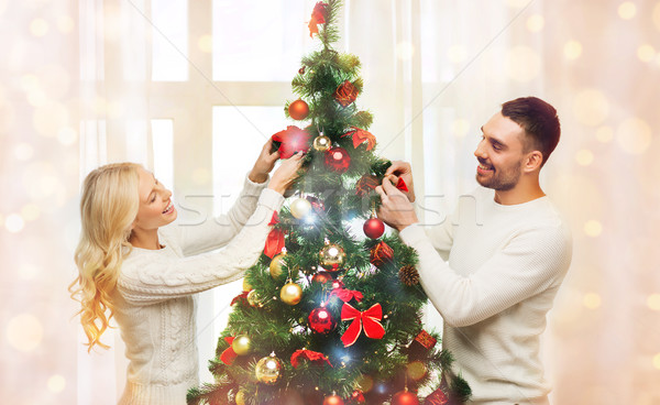 happy couple decorating christmas tree at home Stock photo © dolgachov