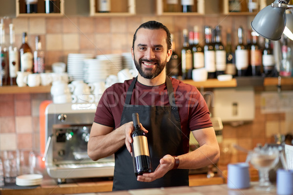 happy man or waiter with bottle of red wine at bar Stock photo © dolgachov