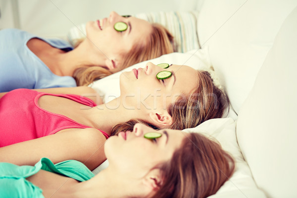 happy young women with cucumber mask lying in bed Stock photo © dolgachov