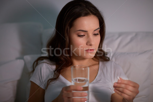 Mujer píldora vidrio agua cama casa Foto stock © dolgachov