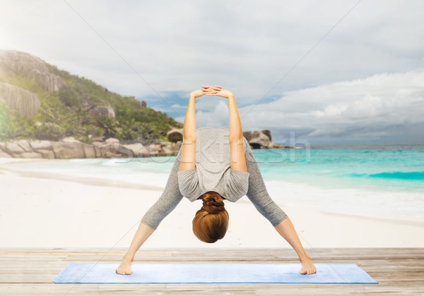 woman doing yoga wide-legged forward bend on beach Stock photo © dolgachov