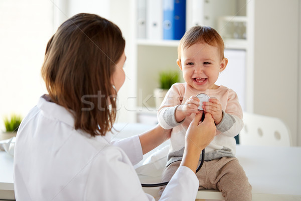 doctor with stethoscope and happy baby at clinic Stock photo © dolgachov