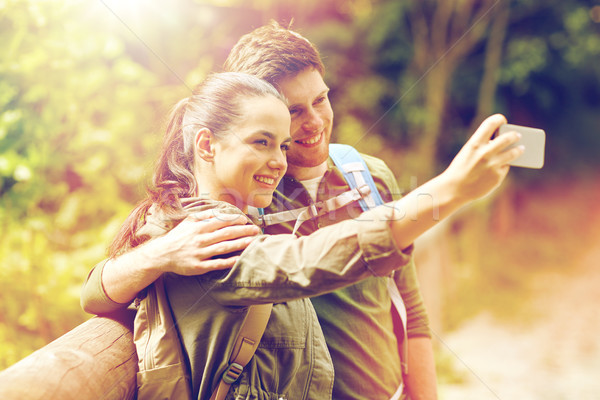 Stock photo: couple with backpacks taking selfie by smartphone