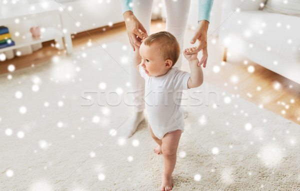 Stock photo: happy baby learning to walk with mother help