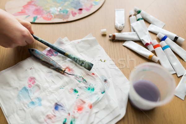 artist hand with paintbrush, paper and paint tubes Stock photo © dolgachov