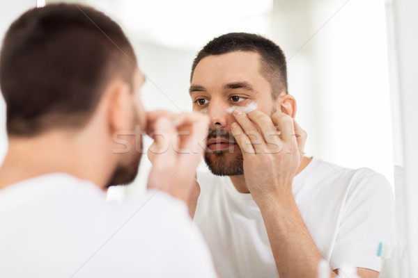 young man applying cream to face at bathroom Stock photo © dolgachov