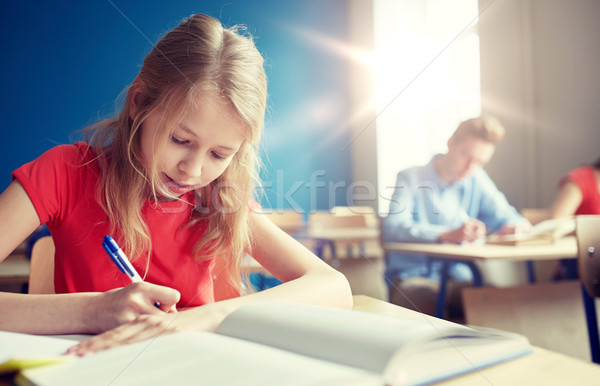 Stock photo: student girl with book writing school test