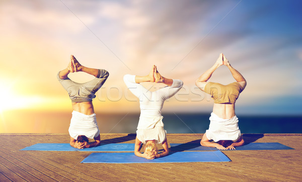people doing yoga headstand on mat outdoors Stock photo © dolgachov