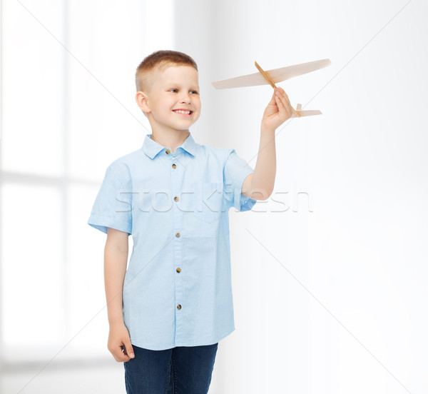 smiling little boy holding a wooden airplane model Stock photo © dolgachov