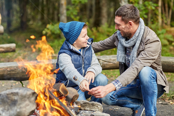 father and son roasting marshmallow over campfire Stock photo © dolgachov