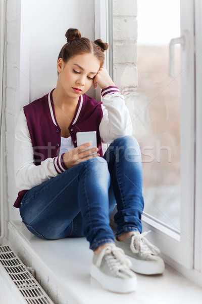 Stock photo: sad pretty teenage girl with smartphone texting