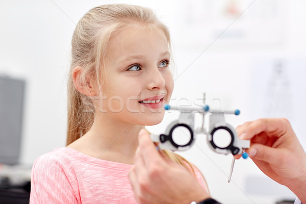 optician with trial frame and girl at clinic Stock photo © dolgachov