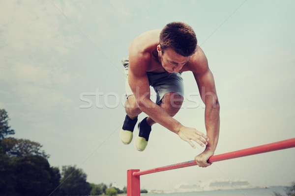 young man exercising on horizontal bar outdoors Stock photo © dolgachov